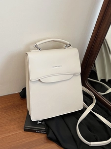 Chic cream leather handbag with top handle and shoulder strap shown in a lifestyle setting