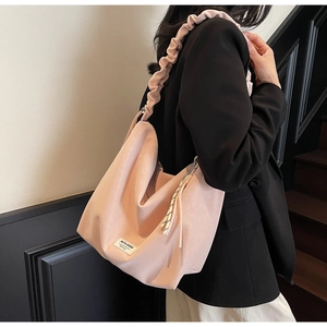 Pink pleated strap tote bag with side striped drawstrings shown on a black blazer