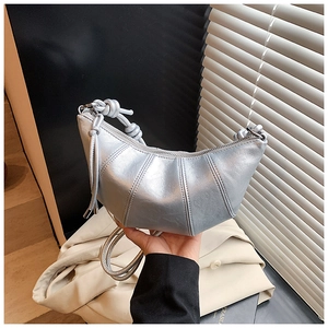 Detail of silver crescent bag featuring vertical pleats and textured knotted strap design