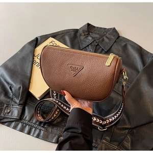 Detailed close-up of brown litchi pattern leather saddle bag with wide jacquard strap