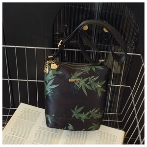 Detail of waterproof nylon bag with green leaf pattern and gold-tone zippers