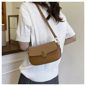 Brown pebble leather shoulder bag with oval metal lock shown on model back view