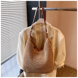 Detailed view of beige crochet hobo bag with brown leather strap hanging on a blazer