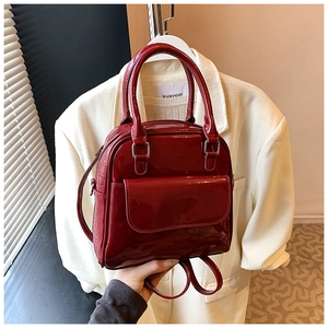 Detail shot of mini dark red patent leather backpack featuring silver hardware accents