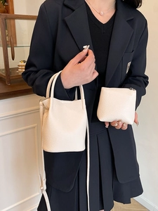 Chic cream white bucket bag with handle and small pouch on female model in navy blazer