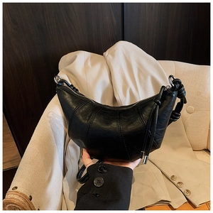Close-up of black crescent shoulder bag featuring pleated details and silver zipper closure