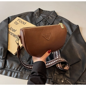 Close-up of brown pebbled leather saddle bag with wide jacquard strap and gold zipper