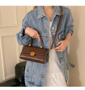 Detail der braunen Vintage Lederhandtasche mit Goldverschluss und Griff, getragen von Model