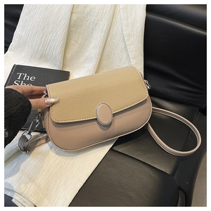 Detail view of two-tone shoulder bag featuring beige lychee grain and silver oval buckle