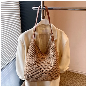 Detail view of woven hobo tote bag with brown leather straps and metal hardware