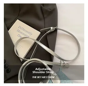 Detail of adjustable silver leather strap with metal buckle on blue denim shoulder bag