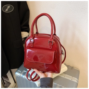 Detailed view of glossy red patent leather top handle handbag with mirror finish
