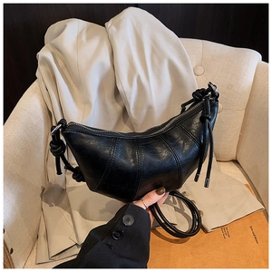 Close-up of black croissant bag with shiny pleated leather and metallic silver zipper
