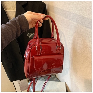 Detail of red patent leather mini backpack featuring silver hardware and flap front pocket