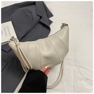 Detail of quilted croissant bag in cream white faux leather with pleated design