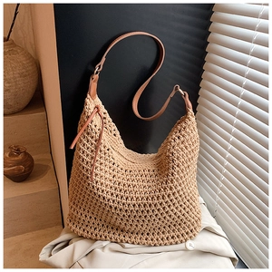 Detailed view of beige woven hobo bag featuring hollow texture and brown leather strap