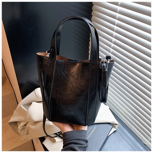 Detail of black glossy leather bucket bag with silver hardware and adjustable strap