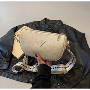 Detail of cream-white lychee grain leather pillow bag with wide woven shoulder strap