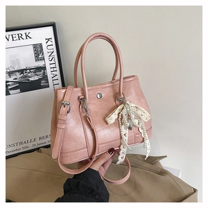 Détail du sac seau rose en cuir avec pendentif en dentelle et ornement de perles