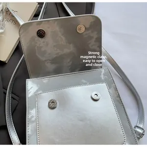 Detail view of mirror silver bag featuring dual magnetic buckle closure and metallic finish