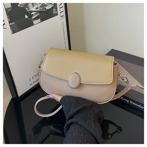 Close-up of beige crossbody bag with pebbled leather flap and silver metal hooks