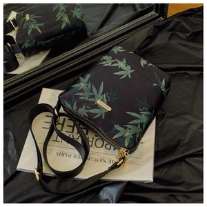 Close-up of waterproof nylon crossbody bag with green leaf patterns and gold logo