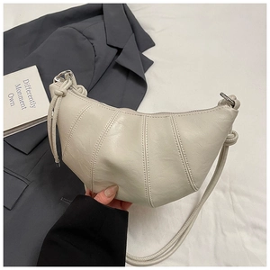 Detail of off-white croissant bag showing segmented stitching and silver hardware