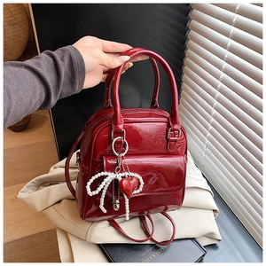 Detail of red patent leather mini bag with pearl bow decoration and heart pendant