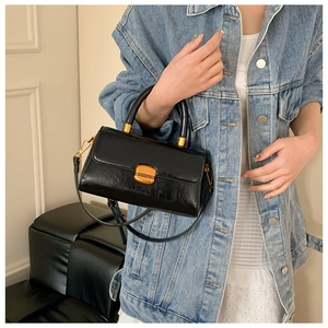 Nahaufnahme der schwarzen glänzenden Lederhandtasche mit elegantem goldenem Metallschloss