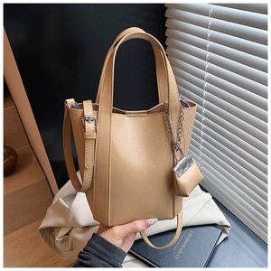 Detail of light brown tote bag showing faux leather texture and mini pouch charm