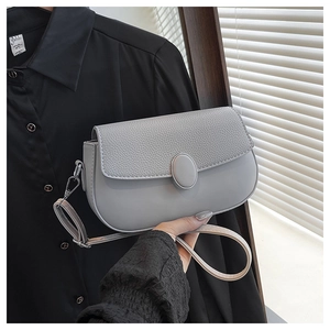 Detail of light grey shoulder bag with lychee grain flap and oval metal buckle closure