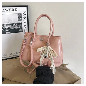 Détail du sac seau rose avec nœud en dentelle, breloque perle et double poignée en PU