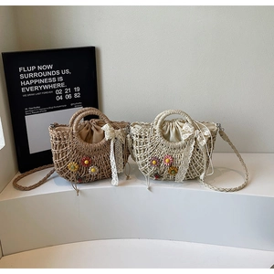 Detail of woven straw bags with daisy embroidery, lace bows and drawstring inner liners