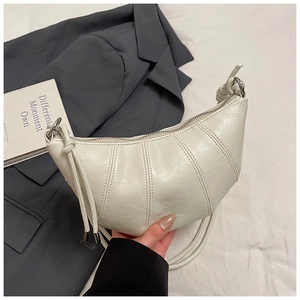 Detail of cream-white crescent croissant bag showing pleated leather and metal zipper