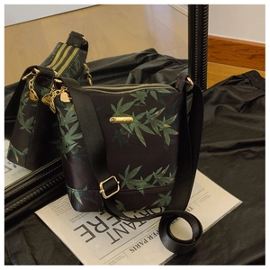 Detail of waterproof nylon crossbody bag with green leaf pattern and gold metal hardware