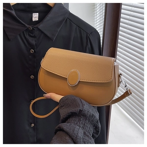 Detailed view of the textured brown leather saddle bag with silver oval buckle and strap