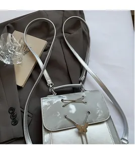 Detail of silver shiny crossbody bag with gold butterfly clasp and lace-up design