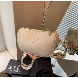 Close-up of cream leather pillow bag featuring geometric embroidered strap and logo