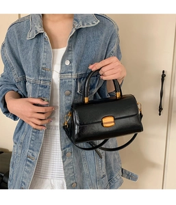 Schicke schwarze Handtasche mit goldenem Verschluss am Modell in Detailaufnahme