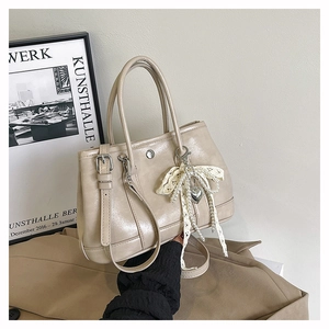 Détail du sac seau beige avec breloque nœud en perles dentelle et boucle en métal