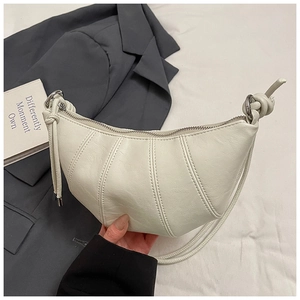 Detail of off-white crescent moon bag showing pleated faux leather and knotted strap design