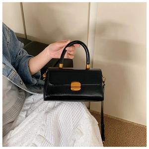 Detail der schwarzen Vintage-Ledertasche mit goldenen Beschlägen und Zylindergriff