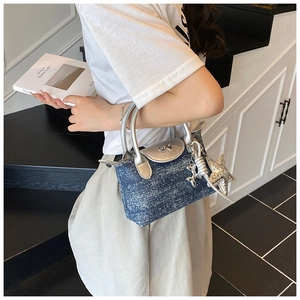 Detail of silver metallic bow and star charm on a denim tote bag with silver handles