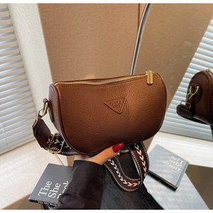 Detail of brown litchi leather pillow bag with wide patterned strap and gold zipper