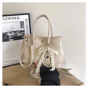 Détail du sac seau beige avec nœud en dentelle de perles et pendentif cœur