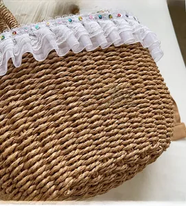 Detail of straw handbag featuring white lace ruffles and colorful sequins embellishment