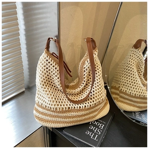 Detail of hollow-out mesh weave and brown leather shoulder strap on beach tote