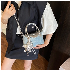 Detailed view of denim crossbody bag with silver bow buckle and sequin star charm