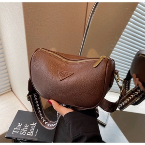 Close-up of brown litchi pattern leather bag with woven wide shoulder strap and gold zipper
