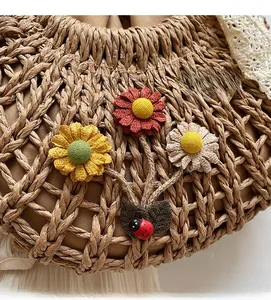 Close-up of handmade straw bag with colorful fabric flowers and ladybug detail